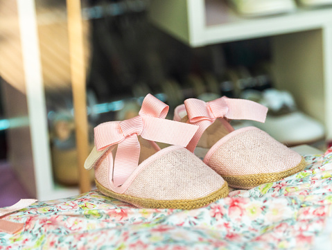 Baby cloth slippers with pink bows, behind a store window