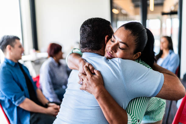 pareja madura abrazada después de hablar en una terapia grupal en un centro de salud mental - couple therapy alternative therapy relationship difficulties fotografías e imágenes de stock