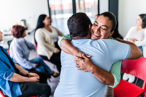 Mature couple embraced after talking in a group therapy at mental health center