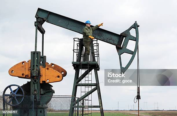 Oil Worker Stands At The Pump Jack Stock Photo - Download Image Now - Oil Worker, Adult, Adults Only