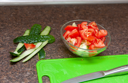 Making of salad from tomatoes and cucumbers.