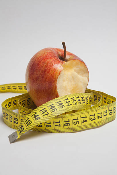 Weight control studio photography concept of losing weight apple with bite out of it stock pictures, royalty-free photos & images