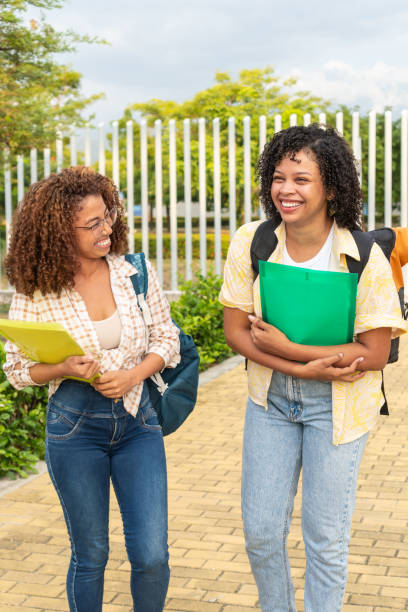 istock Cheerful young students wearing casual clothes and holding folders while walking through university campus on sunny day 1672473145