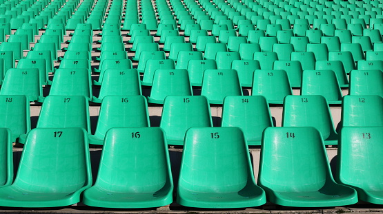 fragment of a stadium tribune with rows of green plastic chairs without people, like a city background, unoccupied seats for fans in the sector for watching sports competitions, city infrastructure without people