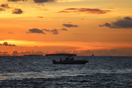 Motor boat at the sea with people. Cloudy sky, Dramatic sunset time. Caribbean region. Anywhere.