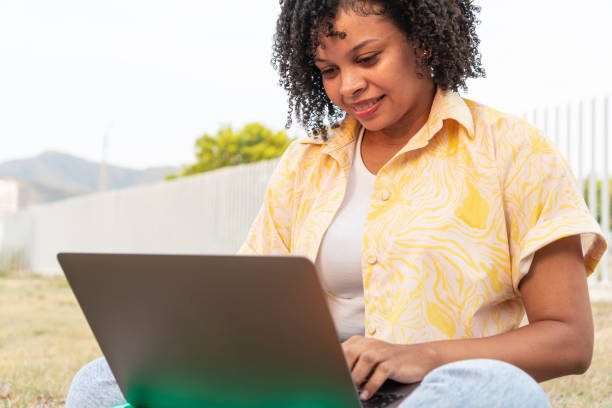 istock Young woman using a laptop in a park 1672483865