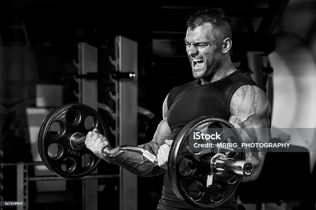 Uomo muscolare facendo esercizi pesanti bilanciere - Foto stock royalty-free di Adulto