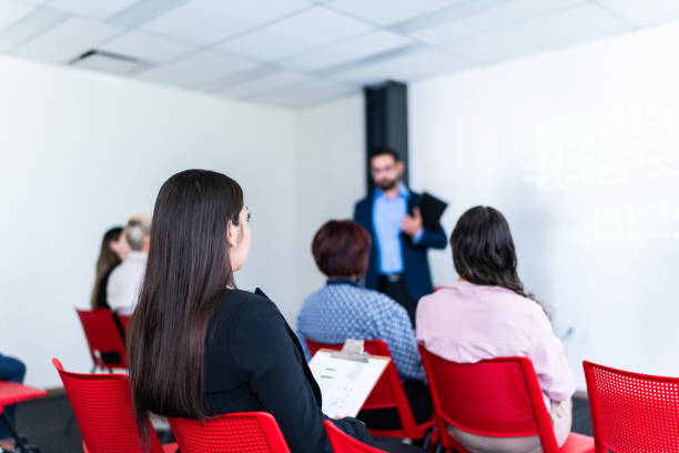 istock Mid adult woman watching a presentation at office 1672500694
