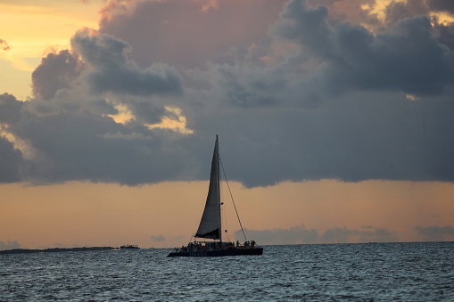Catamaran with sail at the sea with people. Cloudy sky, Sunset time. Caribbean region. Anywhere.