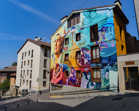 One male, male artist painting a graffiti on the wall on building top.