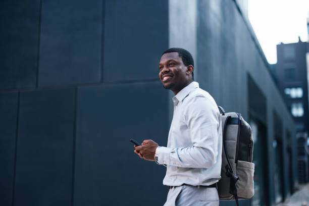istock A Happy Handsome Businessman With A Backpack Looking Away While Using His Mobile Phone 1672555989