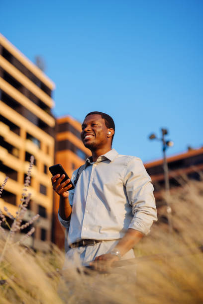 istock A Happy Handsome Businessman With Earbuds Looking Away While Using His Mobile Phone 1672556864
