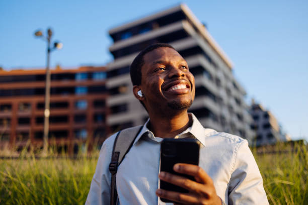 istock A Happy Handsome Businessman With Earbuds Looking Away While Using His Mobile Phone 1672557076