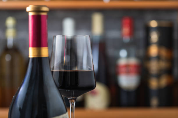 istock Red wine bottle and red wine glass on a wooden table 1672567527