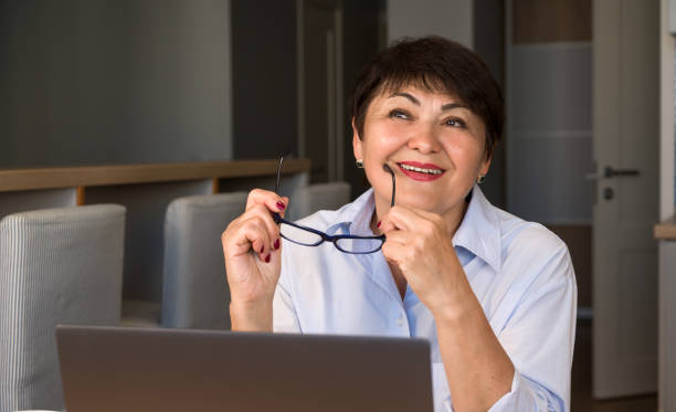 istock puzzled senior woman wearing glasses using laptop while working at home. modern technologies concept. work from home 1672581751
