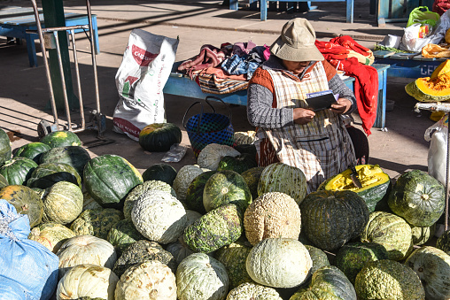 Urubamba, Peru - 30 June 2022: Lady selling vegetables and produce in the Urubamba central market. Sacred Valley, Cusco, Peru