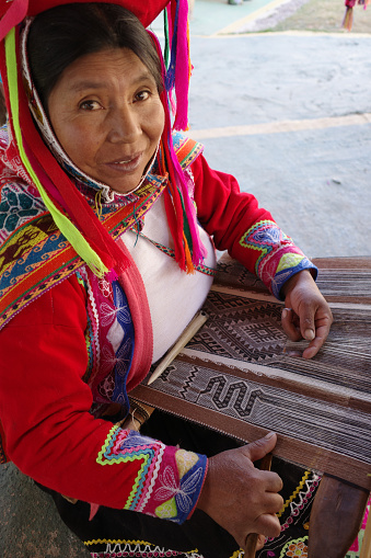 Cusco, Peru - 1 July, 2022: A Quechua lady weaves traditional Andean textiles using alpaca wool