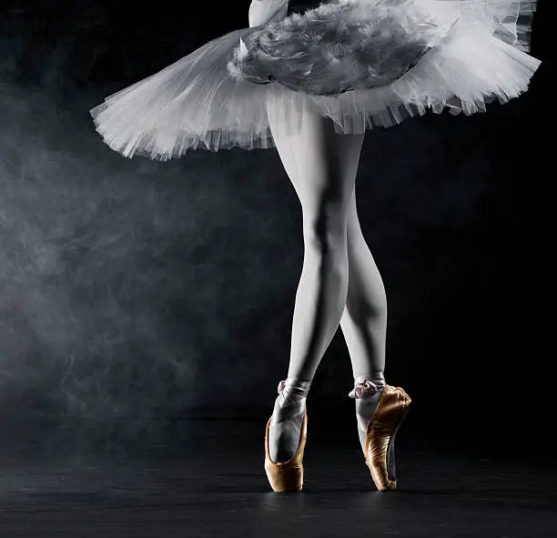 Young female ballerina standing on toes, low section