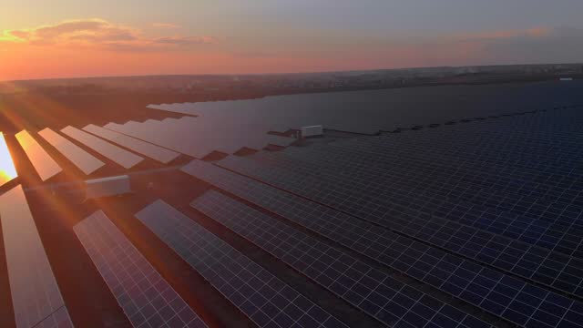 Aerial drone view of large solar panels at a solar farm at bright sunset in early winter. Solar cell power plants