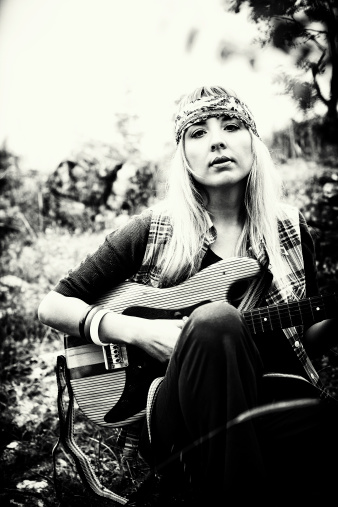 Black and white image of a beautiful hippie with guitar. Shallow depth of field. Visible grain added