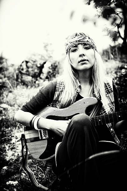Hippie Black and white image of a beautiful hippie with guitar. Shallow depth of field. Visible grain added hippie fashion stock pictures, royalty-free photos & images