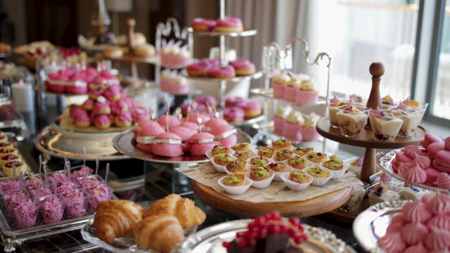 A nice sweet table; macarons, small snacks, sandwiches, pink hamburgers, sweets, cookies, cupcakes. A decorated bridal prep room table, Dessert corner, Candy Bar Wedding, Candy buffet, delicious Candy bar at a wedding