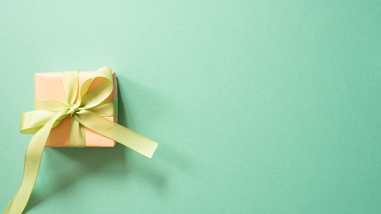 Coral gift box isolated on mint green background. top view, copy space