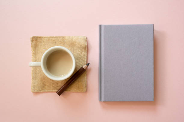 istock Cup of coffee and diary notebook, colored pencil isolated on pink background. top view, copy space 1672653153