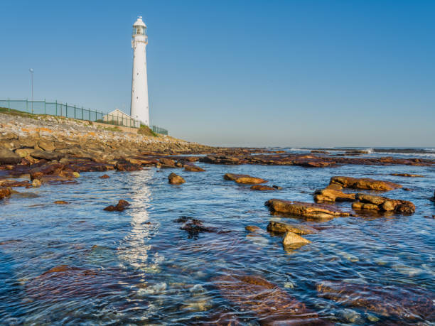 スランコップ灯台と晴れた午後の海水への反射、コメチエ、ケープタウン、南アフリカ - slangkop ストックフォトと画像