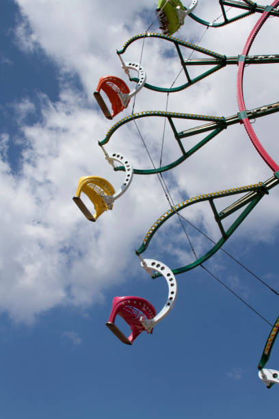 los coches de la noria giratoria parecen volar a través de un cielo de verano - dallas texas texas ferris wheel carnival fotografías e imágenes de stock