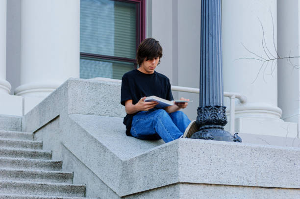 One teenage Latino boy sitting on the school steps studying.Taken in Santa Cruz, California, USA