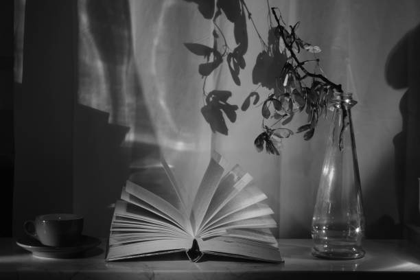 istock Open Book and a vintage vase with branch and coffee cup,reading,education,learning, international book fair concept, black and white shot 1672726135