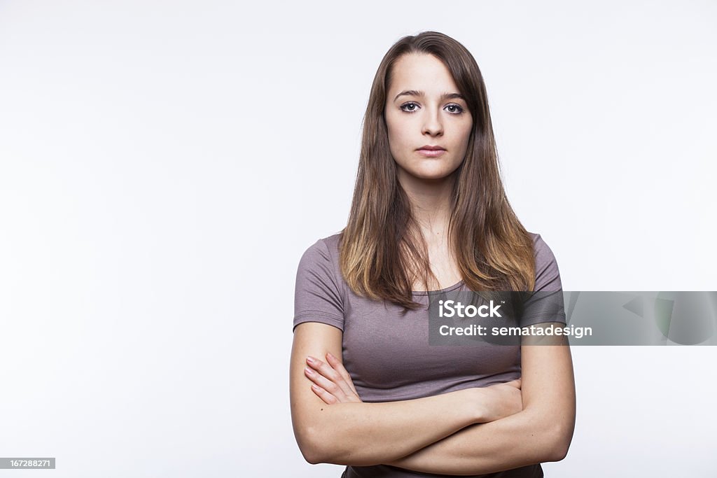 Serious Young Woman With Arms Crossed Portrait of a young woman on a white background. Women Stock Photo