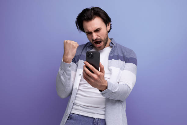 istock lucky brunette guy in casual style with a smartphone in his hands 1672903444