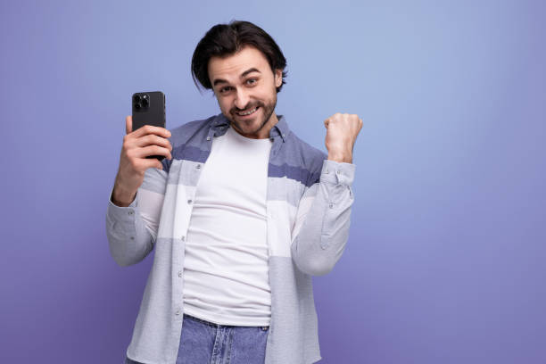 istock joyful young brunette man watching match on smartphone 1672903946