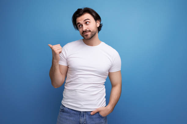 istock young man in a white t-shirt points his finger to the side on a studio background with copyspace 1672904010