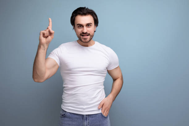 istock pensive brunette young man in a white t-shirt on a studio background with copyspace 1672904023