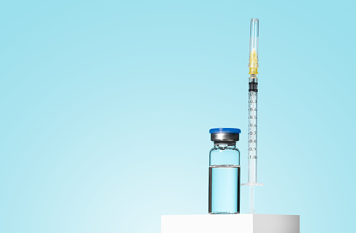 Glass Medicine Vial jar botulinum toxin with medical white injectable syringe on blue background. A preparation for cosmetology rejuvenating procedures, biorevitalization, mesotherapy, anti age. Mock up