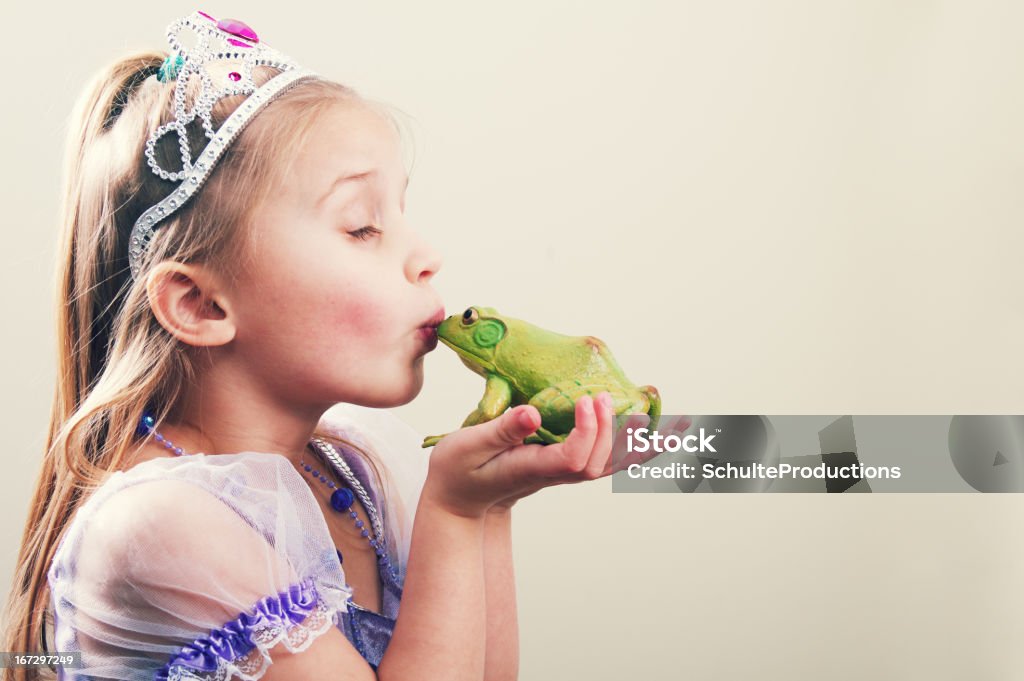 Princess Kissing a Frog a little girl princess kissing a frog with copy space. Fairy Tale Stock Photo