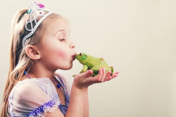 Princess Kissing a Frog a little girl princess kissing a frog with copy space. prince royal person photos stock pictures, royalty-free photos & images