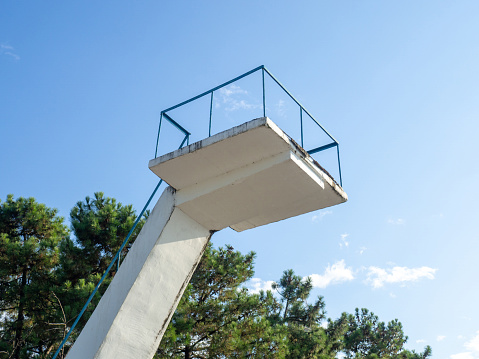 Old diving board. Cement tower on the beach. Against the sky. Resort infrastructure. In a swimming pool