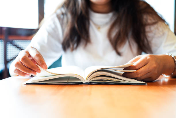 istock Close-up woman reading a book on table 1672993513