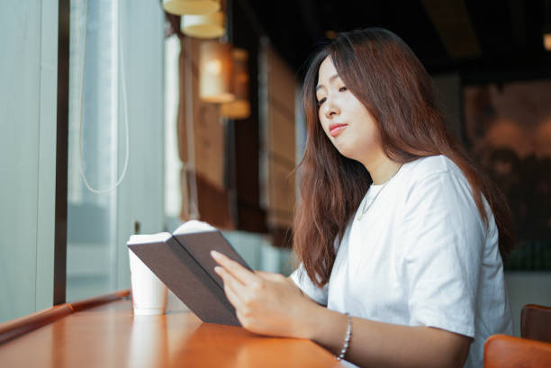 istock Woman reading a book at cafe 1672993543