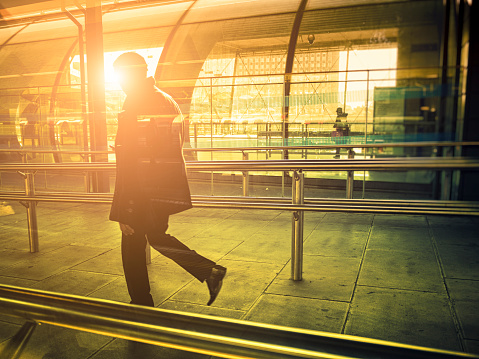 Businessman walking in a contemporary station against sunlight, London.