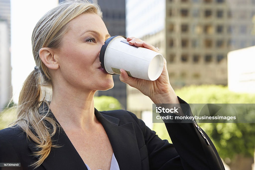 Donna d'affari di bere il caffè da asporto fuori ufficio - Foto stock royalty-free di Bere