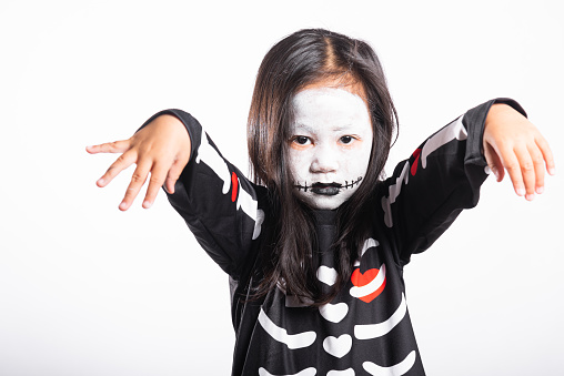 Halloween Kid. Child woman horror face painting make up for ghost scary, Portrait of Asian little kid girl wearing witch costume studio shot isolated white background, Happy halloween day concept