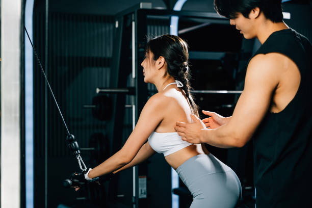 istock Male fitness coach teaching a woman how to use a pulldown cable machine 1673056073