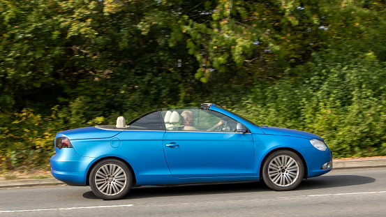 Milton Keynes,UK-Sept 10th 2023: 2008 blue soft top Volkswagen EOS Sport TDI  car travelling on an English road.