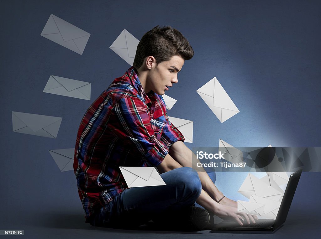 Młody mężczyzna otrzymujący ton wiadomości na laptop - Zbiór zdjęć royalty-free (E-mail)