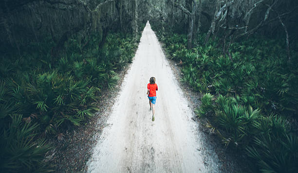 solitário homem executado sob árvores na estrada ao pôr do sol - georgia sunlight healthy lifestyle cumberland island imagens e fotografias de stock